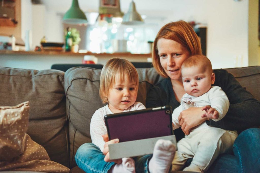 Mother using tablet with her two young kids