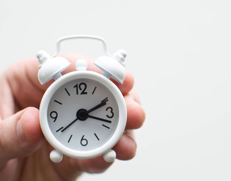 Parent's hand holding small white clock to show about time management